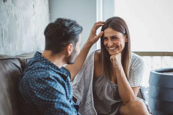 Man and woman on a date in Boston, she is smiling as he touches her hair
