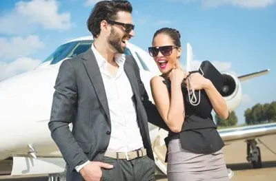 Wealthy couple standing in front of a small private jet