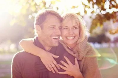 Woman hugging a man in a Chicago park, they are both smiling and happy.