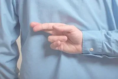 Man's crossed fingers behind his back