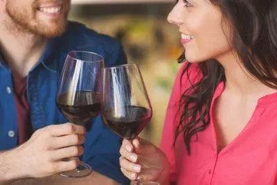 Couple on a first date smiling at each other and toasting with wine