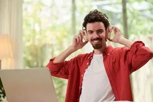 Man wearing headphones and smiling as listens to a dating podcast