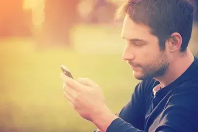 Defeated-looking man staring at Bumble on his cell phone