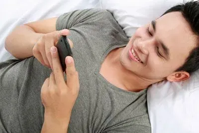 Man texting in bed to a Bumble match