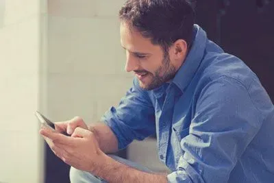 Smiling man using OkCupid on mobile