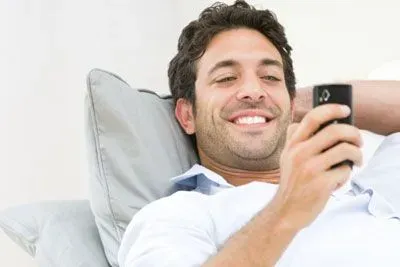 Reclining man using his cell phone and smiling