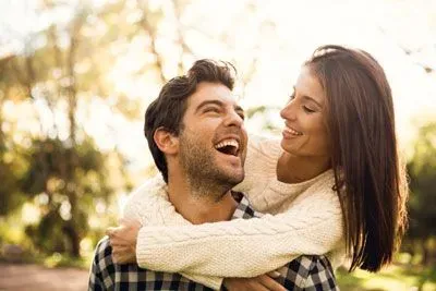 Woman embracing man from behind while they smile at each