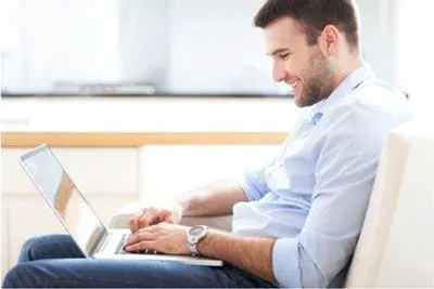 Smiling man using eHarmony on a laptop