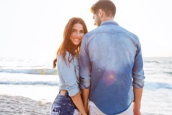 couple on a date at the beach with the woman smiling at the camera