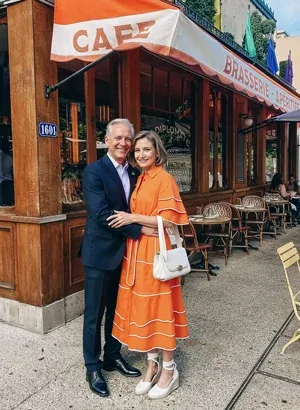Couple who met through a millionaire matchmaker posing in front of a quaint cafe.