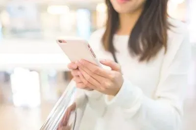 Woman holding her mobile in two hands and reading Facebook messages