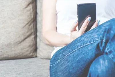 Woman sitting on her couch and holding her phone