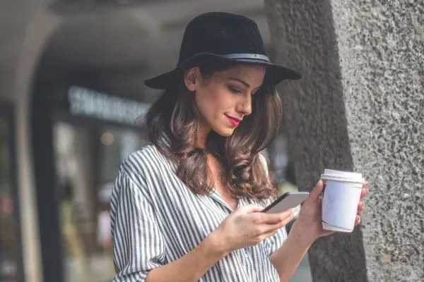 Pretty woman looking at Tinder message and holding a coffee cup