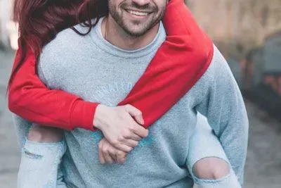 Smiling man giving a woman a piggyback ride