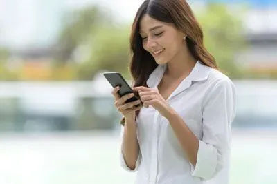 Young woman outside using Tinder on her phone