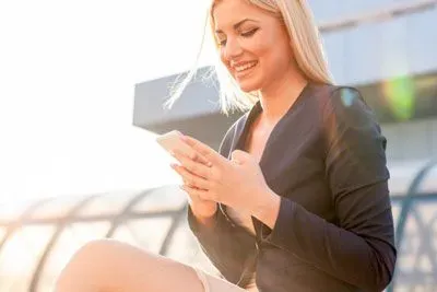 Woman sitting outside using Bumble on her phone