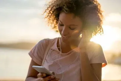 Woman with earbuds listening to a voice prompt on Hinge