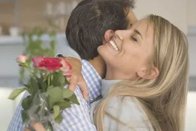Woman hugging man who just gave her red roses