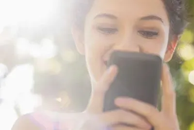 Smiling young woman texting on Tinder and smiling